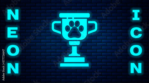 Glowing neon Pet award symbol icon isolated on brick wall background. Medal with dog footprint as pets exhibition winner concept. Vector.
