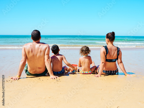 Family of four seated on the beach sand