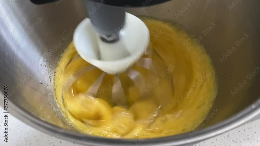Slow motion clip of eggs being whisked in a bowl of a food mixer. Pandemic lockdown baking in effect. Everyone is taking up baking. Slow motion clip of eggs being whisked in a bowl of a food mixer. Pandemic lockdown baking in effect. Everyone is taking up baking.