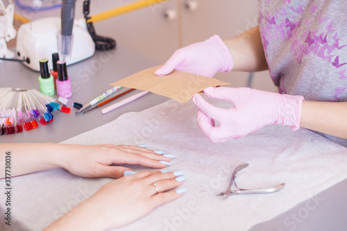 The manicurist opens an individual package with tools. Disinfection and sterilization. Safety.
