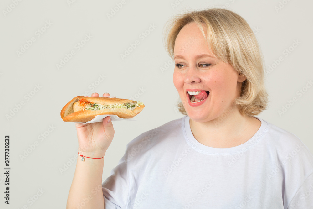 beautiful young plump woman in a white t-shirt on a white background with a sandwich in her hand beautiful young plump woman in a white t-shirt on a white background with a sandwich in her hand