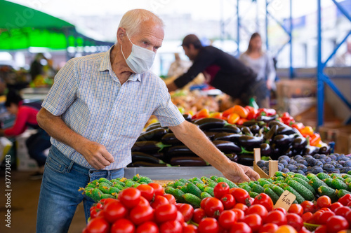 retired european man wearing medical mask protecting against virus buying tomatoes in market