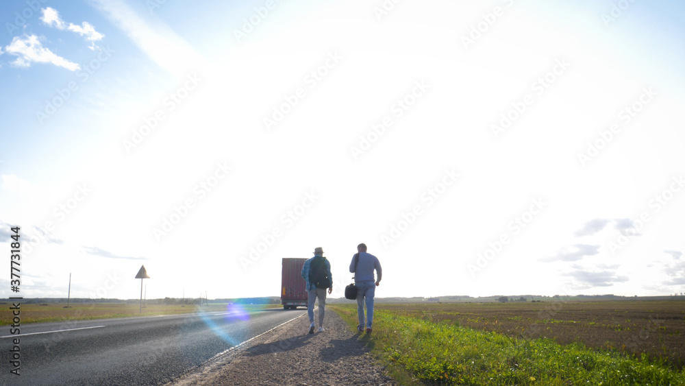 Fototapeta premium Asphalt road on dandelion field with a small truck. lorry moving on sunny evening.