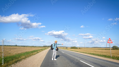 A young man is hitchhiking around the country. The man is trying to catch a passing car for traveling. The man with the backpack went hitchhiking to south. © dkHDvideo