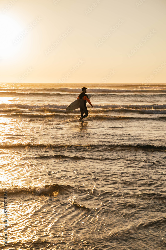 Young surfer entering the sea with board in hand to surf