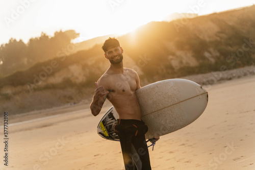 Portrait of young surfer with wetsuit and board in hand