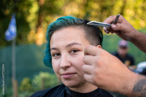 cutting a woman’s hair which green hair