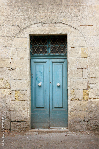 Typical Maltese blue wooden old door on the limestone wall. Malta. Concept of traditional Maltese street view, vintage architecture.