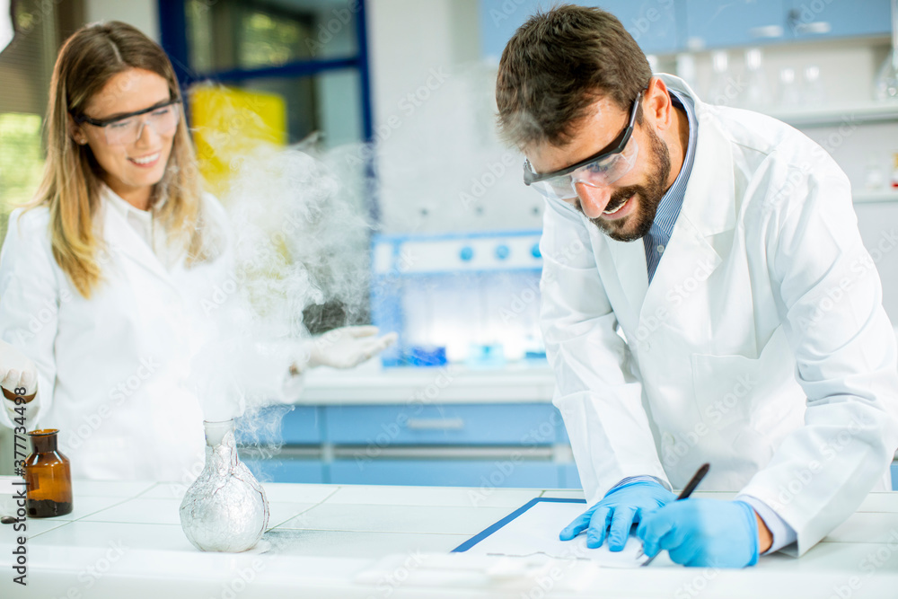 Researchers doing experiment with smoke on a table of a chemical laboratory Researchers doing experiment with smoke on a table of a chemical laboratory