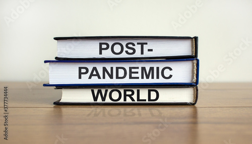 Books with text 'post-pandemic world' on beautiful wooden table, white background. Business and post-pandemic concept. Copy space.
