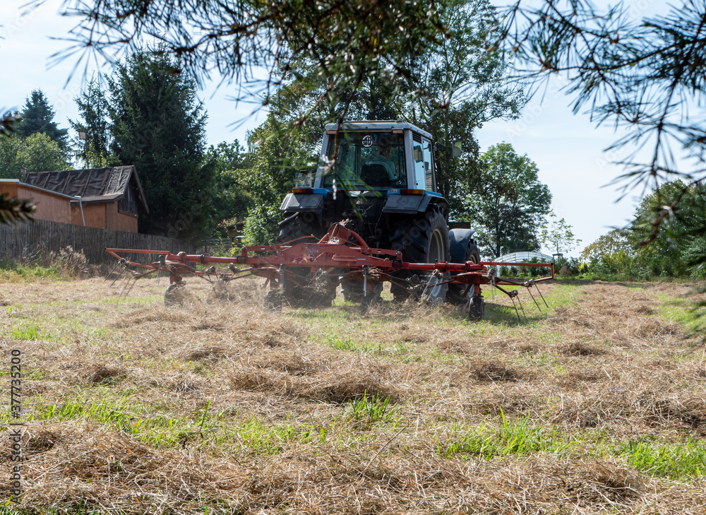 Obraz premium Bauer tut mit Traktor Heu wenden