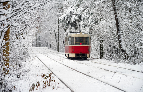 Old red yellow tram rides through the snowy forest. Winter plot. Selective focus.