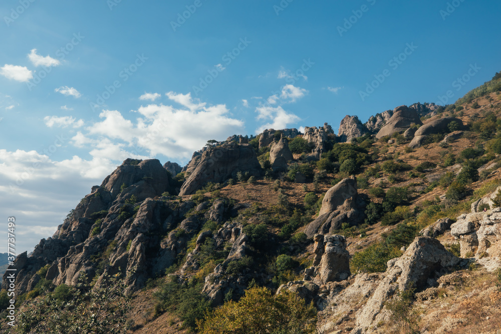 Ridge of brown rocks covered with greenery against a blue sky