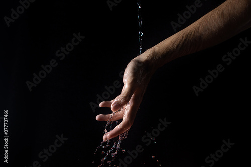 Water on a black background. Water runs down the hand. Pure water