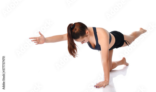 Woman in a sports uniform shows how to perform exercises on a white background.