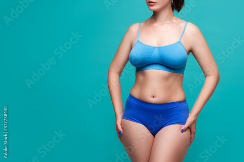 Beautiful sexy woman in blue underwear on turquoise background, perfect female body © staras
