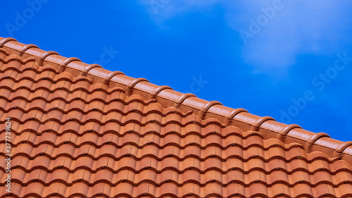 Part of orange roof tile against blue sky in diagonal view