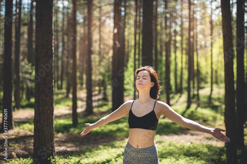 Happy woman with open hands against high trees and pine forest background. Person enjoy nature after yoga practicing. Freedom and imagination concept