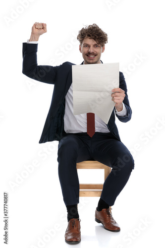 handsome excited businessman holding the newspapaer and celebrating succes photo