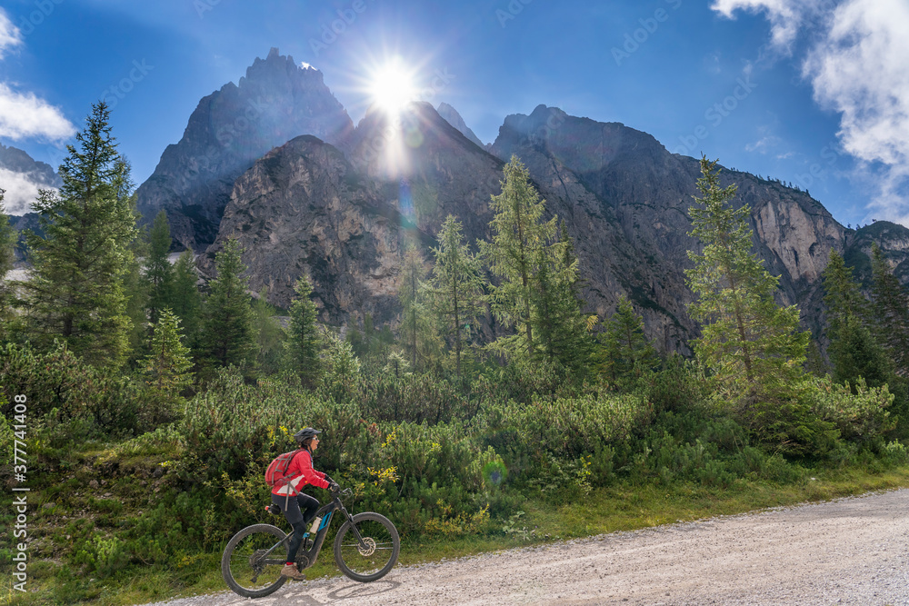 Fototapeta premium pretty senior woman riding her electric mountainbike in the Innerfeld Valley in the Sexten Dolomites near village of Innichen , Tre cime National park, South Tirol, Italy 