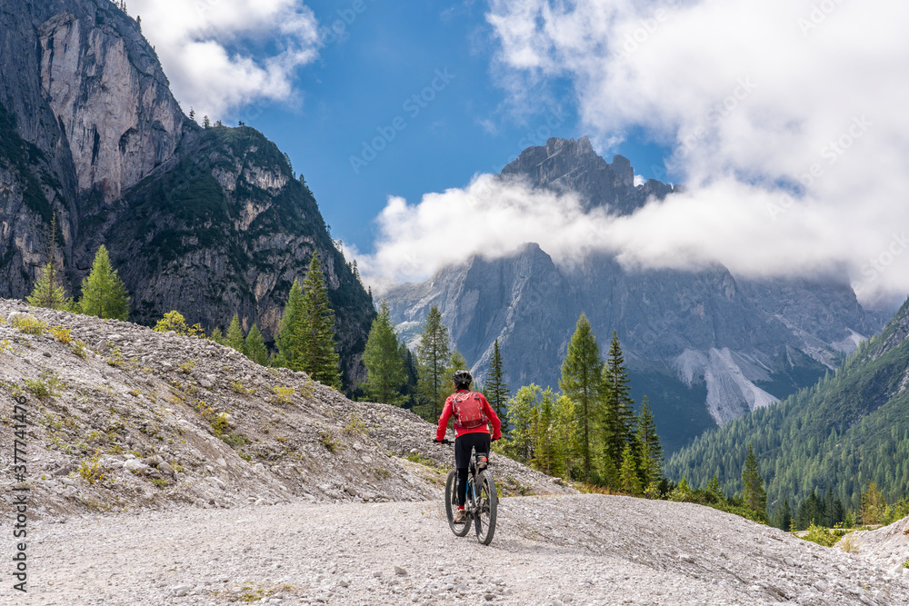 pretty senior woman riding her electric mountainbike in the Innerfeld Valley in the Sexten Dolomites near village of Innichen , Tre cime National park, South Tirol, Italy 