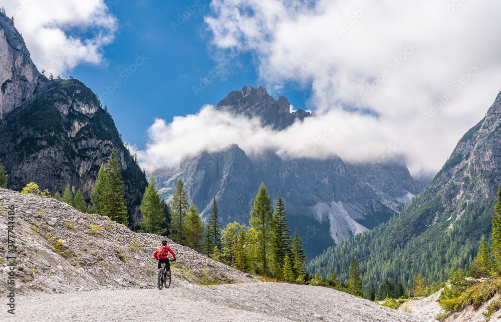 pretty senior woman riding her electric mountainbike in the Innerfeld Valley in the Sexten Dolomites near village of Innichen , Tre cime National park, South Tirol, Italy 