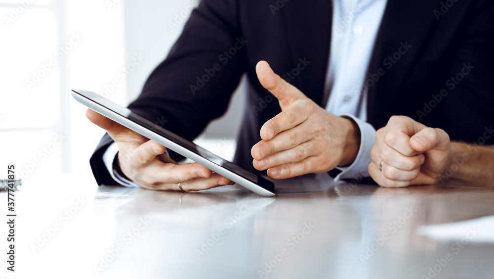 Business people using tablet computer while working together at the desk in modern office. Unknown businessman or male entrepreneur with colleague at workplace. Teamwork and partnership concept Business people using tablet computer while working together at the desk in modern office. Unknown businessman or male entrepreneur with colleague at workplace. Teamwork and partnership concept