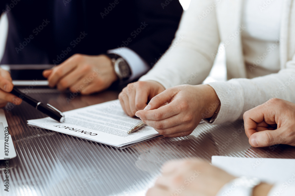 © Iryna - Business people discussing contract working together at meeting in modern office. Unknown businessman and woman with colleagues or lawyers at negotiation