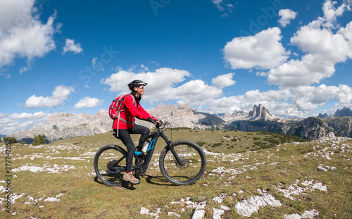 nice senior woman, riding her electric mountain bike below the famous Three peak of Lavaredo in the Sexten Dolomites in South tyrol, Italy