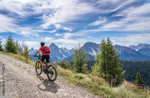 nice and active senior woman riding her electric mountain bike on a old military road from Toblach upt to the summit of Marchkinkele eith spectacular view to the Three peaks of Lavaredo, South Tirol,  © Uwe