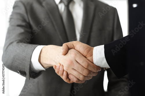 Unknown diverse business people are shaking hands finishing contract signing, close-up. Business and handshake concept