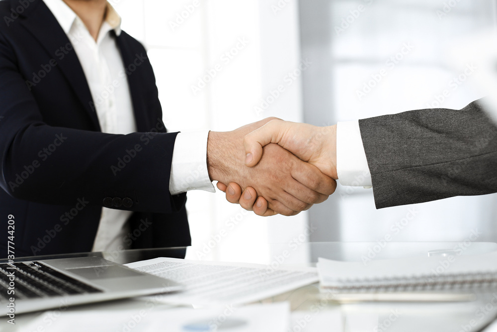 Unknown diverse business people are shaking hands finishing up meeting at the desk in office, close-up. Handshake concept Unknown diverse business people are shaking hands finishing up meeting at the desk in office, close-up. Handshake concept