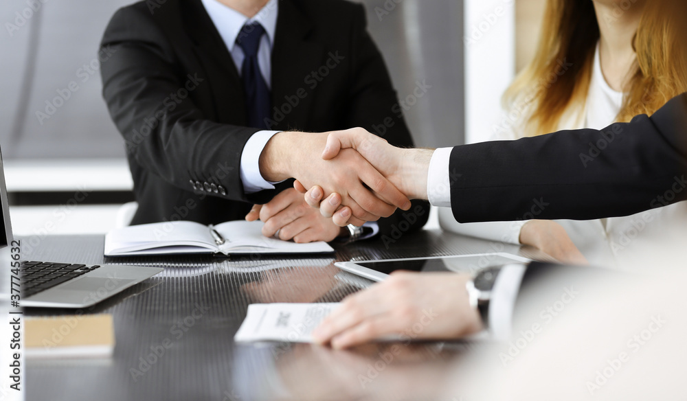 Unknown businessmen shaking hands above the glass desk in a modern office, close-up. Unknown business people at meeting. Teamwork, partnership and handshake concept Unknown businessmen shaking hands above the glass desk in a modern office, close-up. Unknown business people at meeting. Teamwork, partnership and handshake concept