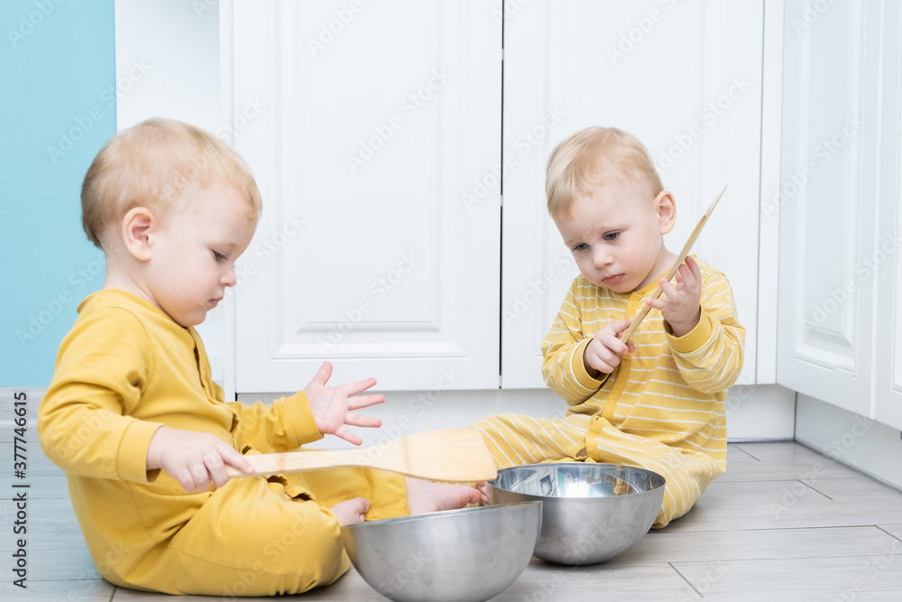 Twin boys play in the kitchen with kitchenware. Twin boys play in the kitchen with kitchenware.