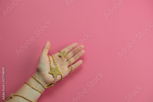 top view hand with golden bracelet star on a pink backgroun