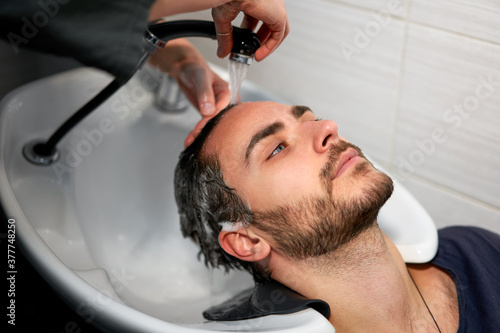 Woman applying shampoo massaging hair customer Man wash hair in beauty salon Hairdresser washing hair. Happy caucasian guy enjoy service in barbershop