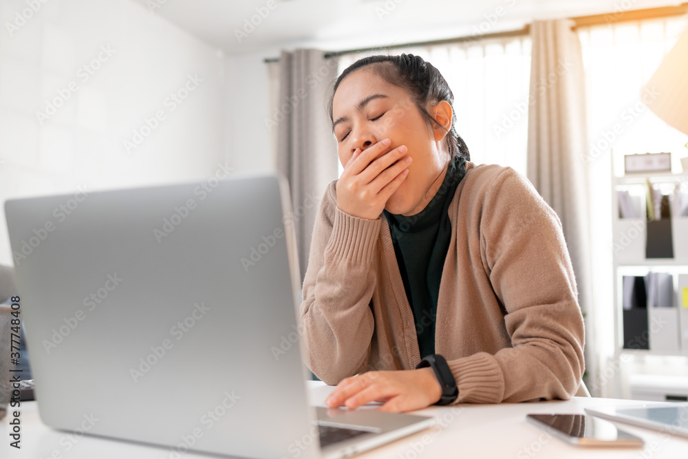 Tired woman yawning and working at home. Tired woman yawning and working at home.