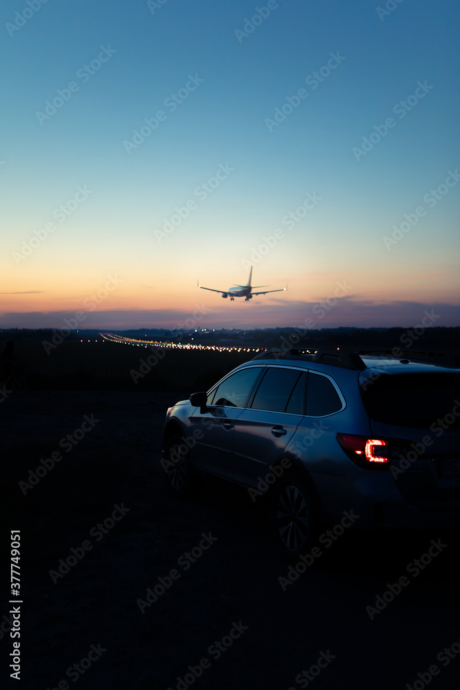 view of the car with taillights airplane landing on background