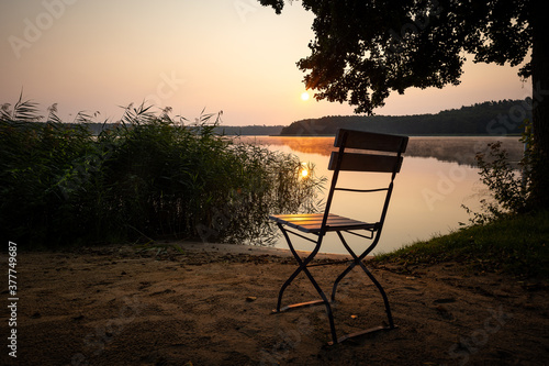 einfach mal Ruhe,  Gartenstuhl bei Sonnenaufgang am See photo