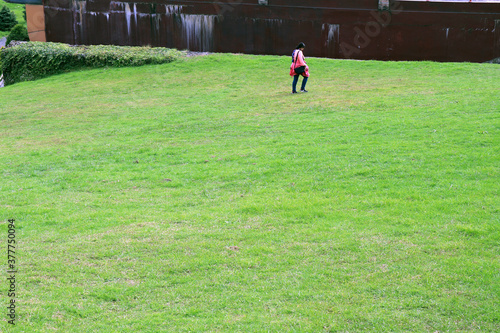 Ravangla, Sikkim, India on 20th October in 2019 :- Young lady is walking in the green grass field. Nature landscape with green grass at Buddha Park of Ravangla in South Sikkim, India.