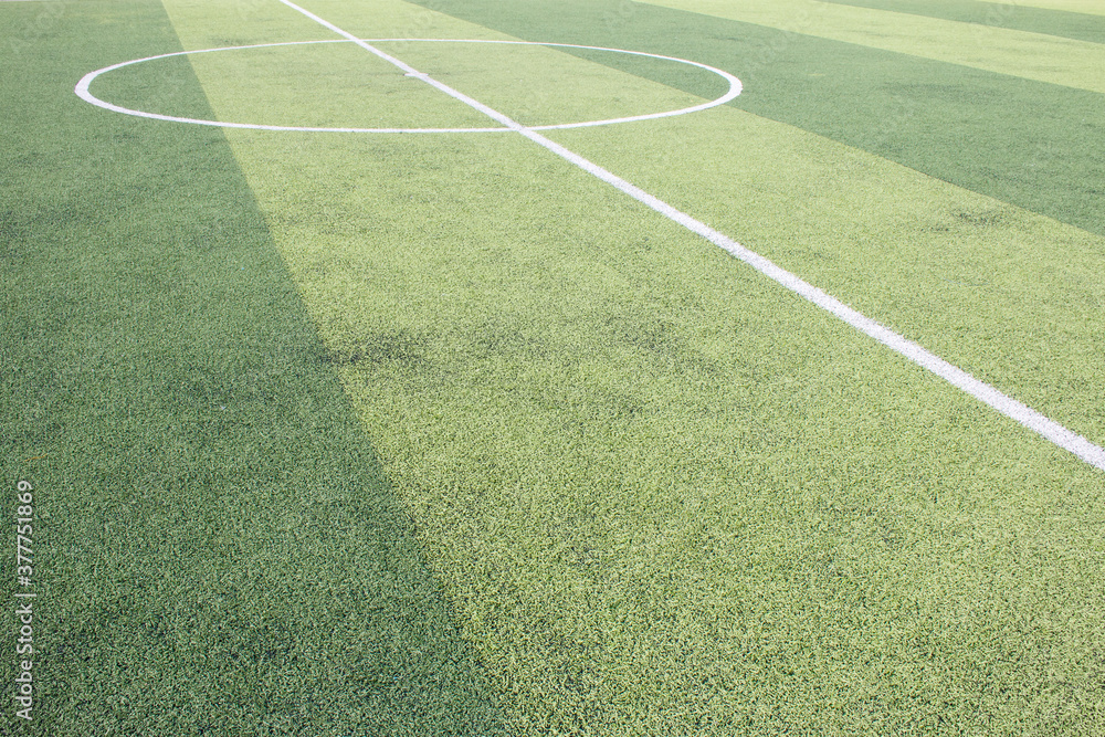 Photo of a green synthetic grass sports field with white line shot from above.