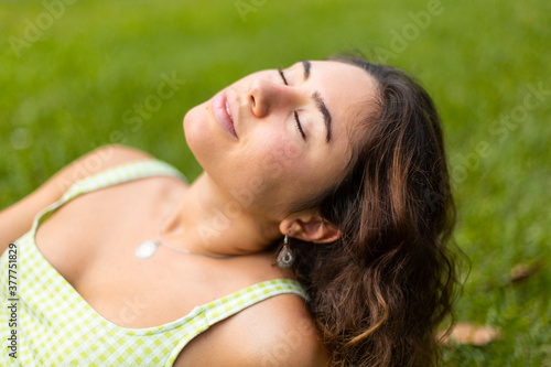 Closeup of young girl with closed eyes with grass background.