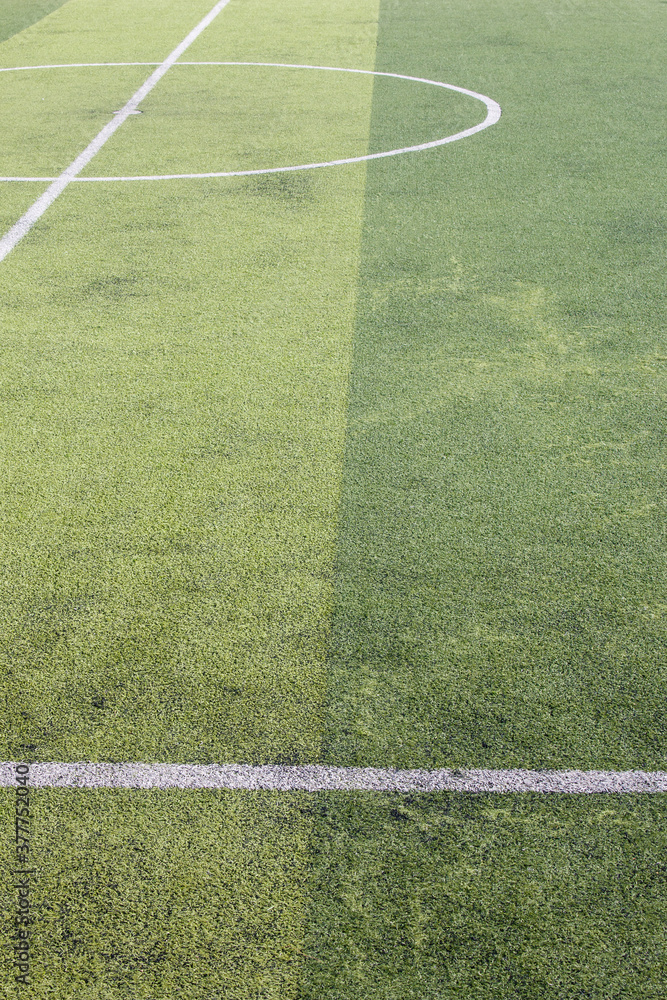 Photo of a green synthetic grass sports field with white line shot from above.