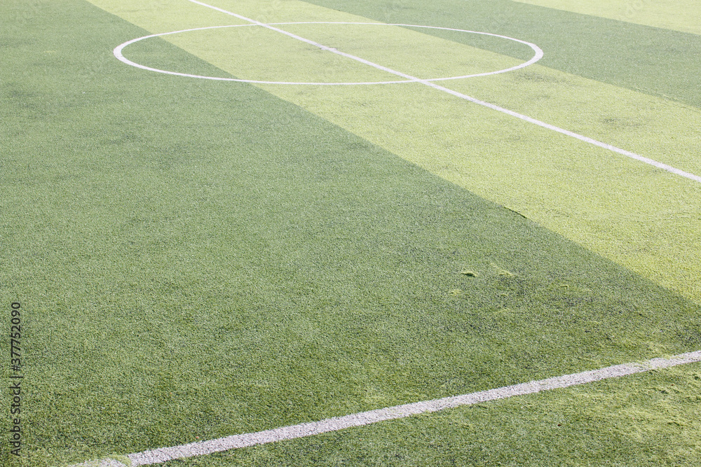 Photo of a green synthetic grass sports field with white line shot from above.