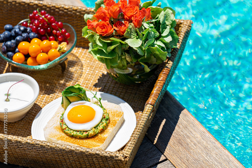 tray with assorted breakfast meal and drinks near swimming pool tray with assorted breakfast meal and drinks near swimming pool