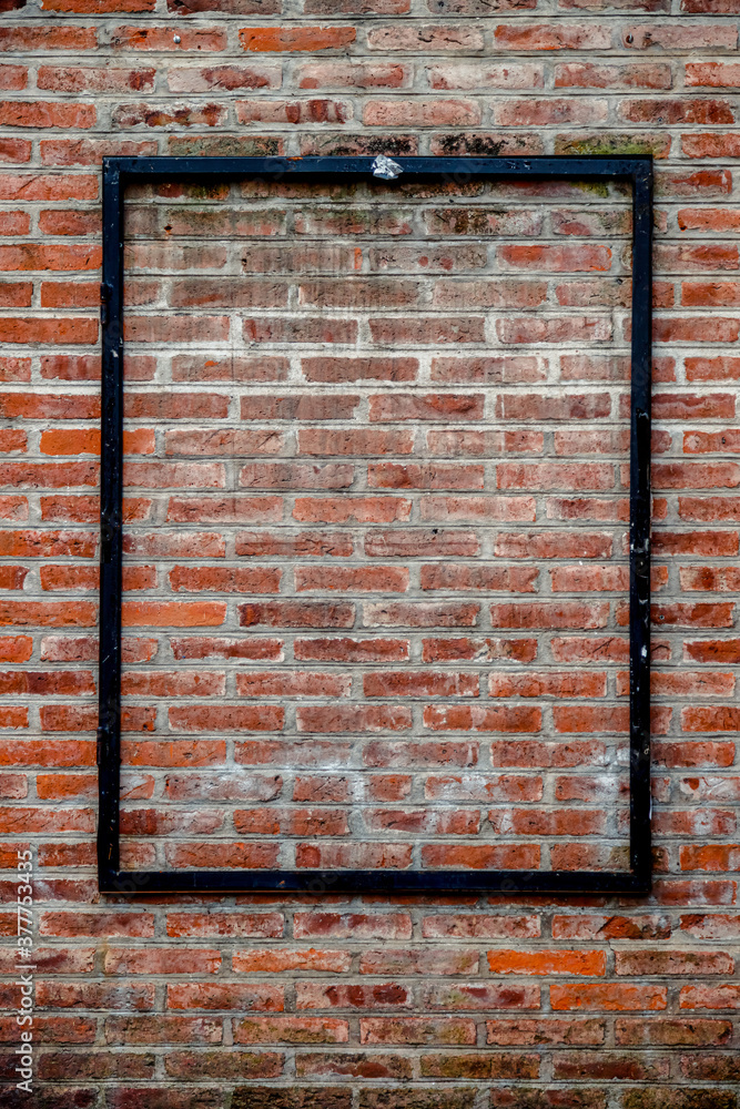 Naklejka premium Black metal frame for advertisement on brick wall