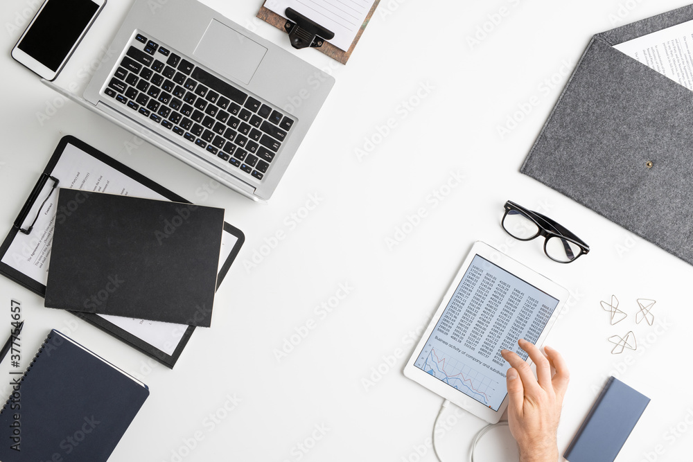 Flatlay of hand of contemporary economist using tablet while analyzing data Flatlay of hand of contemporary economist using tablet while analyzing data