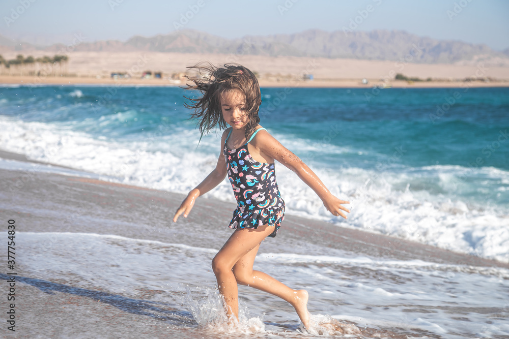 Portrait of a cheerful little girl in a bathing suit by the sea Portrait of a cheerful little girl in a bathing suit by the sea