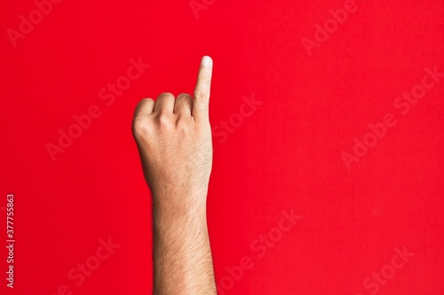 Arm of caucasian white young man over red isolated background showing little finger as pinky promise commitment, number one