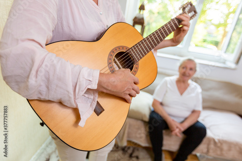 a woman plays something on the guitar for an old lady